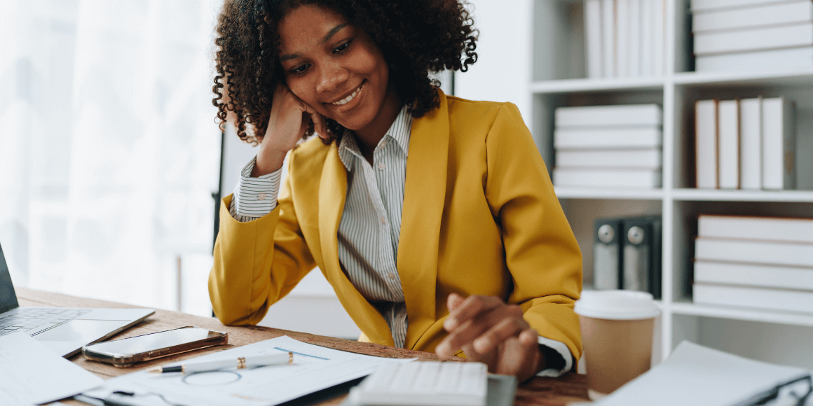 A woman sitting at a desk and using a calculator. 